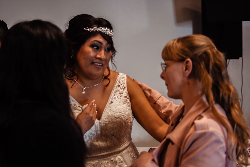 A bride in a sparkly white dress gets ready with her styling team before the ceremony.