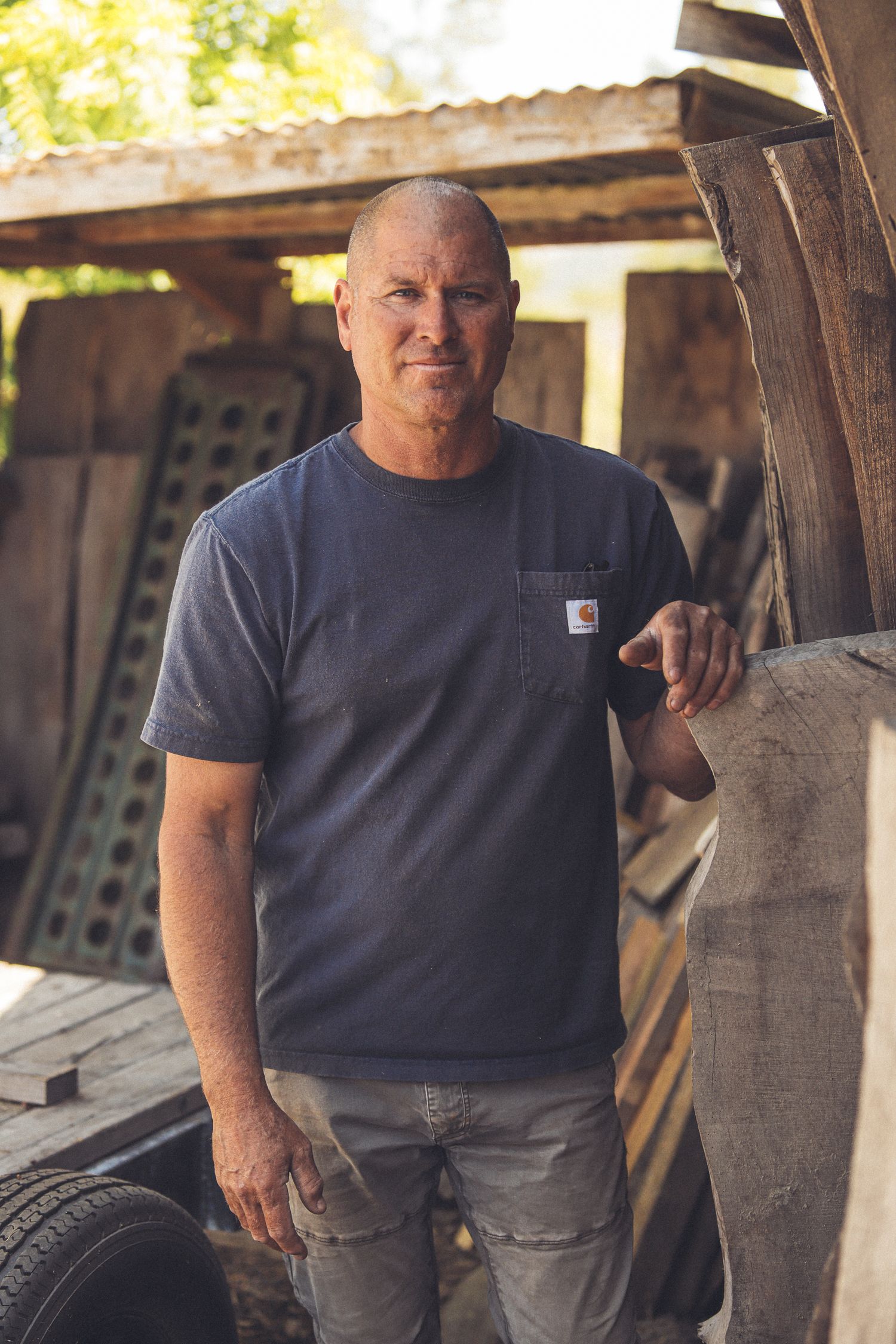 Person wearing a dark t-shirt and gray pants working in a rustic workshop or barn setting.