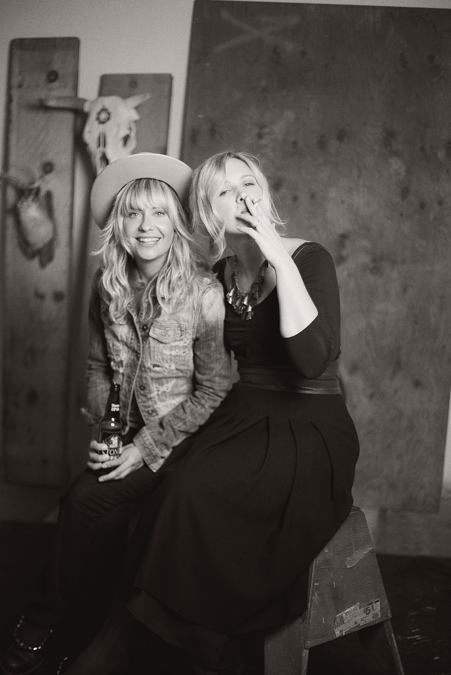 A black and white photo series shows two people sitting together and laughing in a casual, candid setting.
