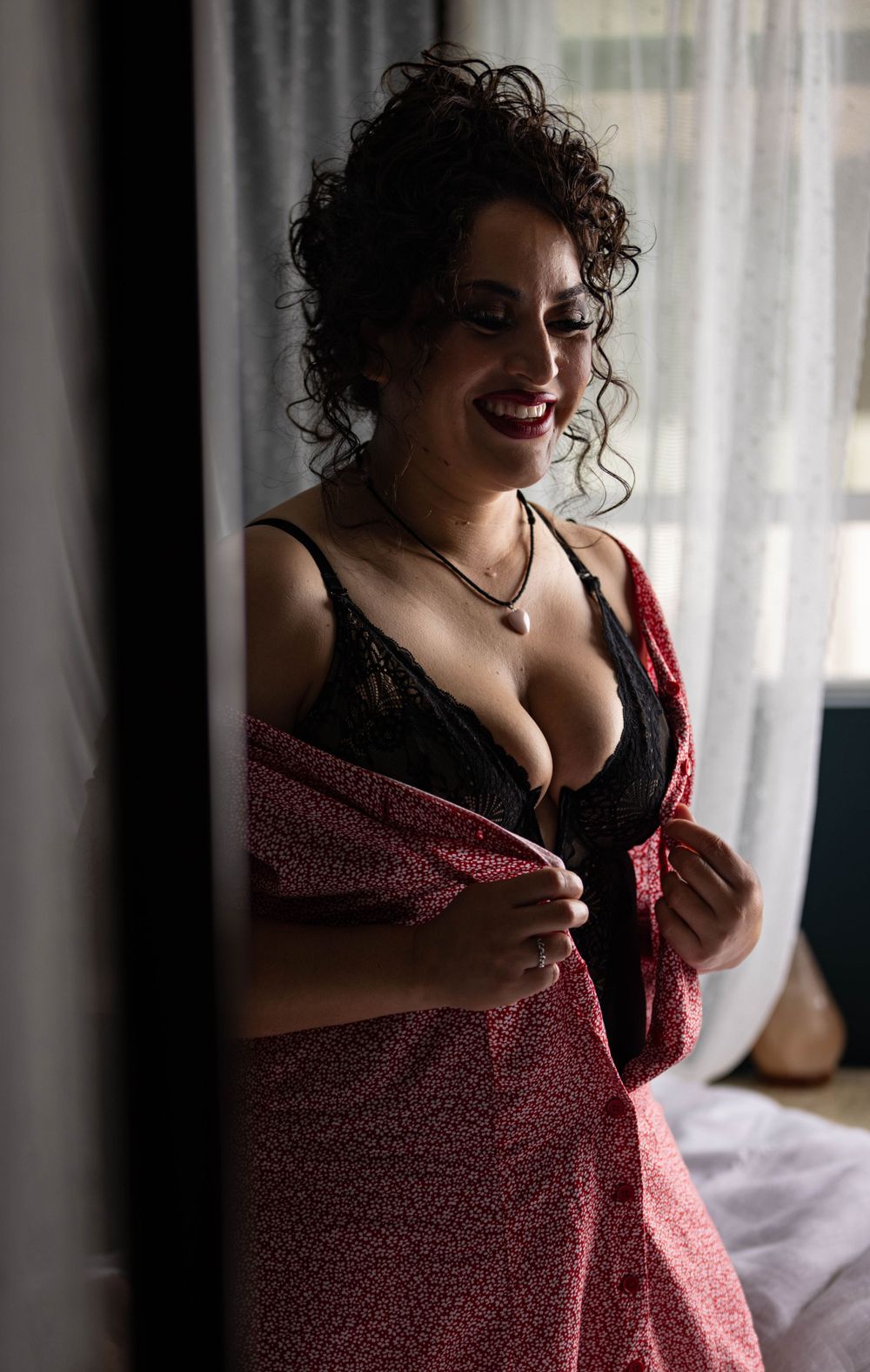 Woman undressing in bedroom captured by Los Angeles boudoir photographer.