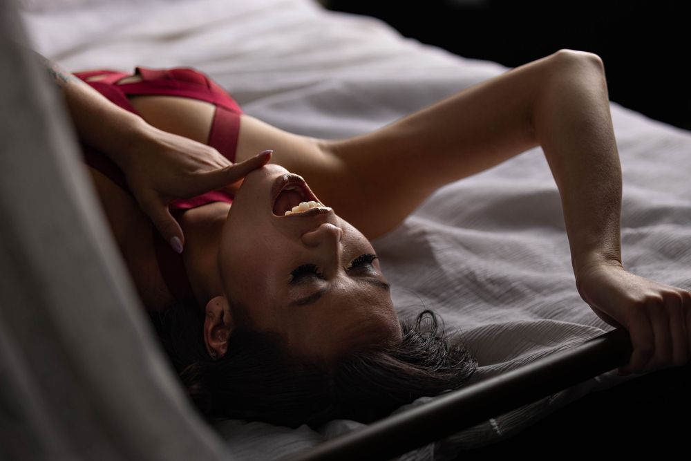 Woman lying in bed wearing lingerie during boudoir photo shoot in Los Angeles.