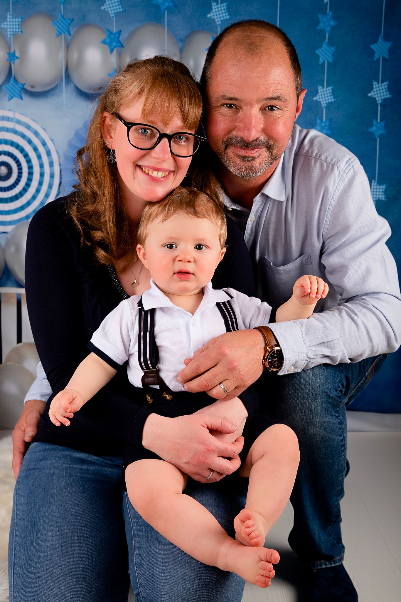 Family portrait with blue and white star backdrop and festive decorations.