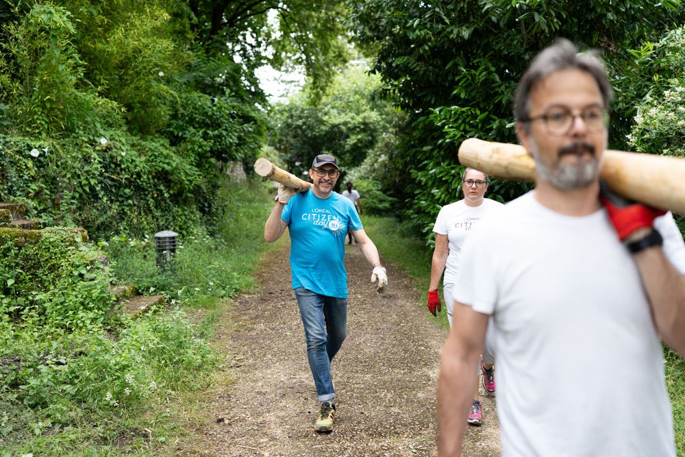 People enjoying a walk along a wooded dirt trail on a sunny summer day.