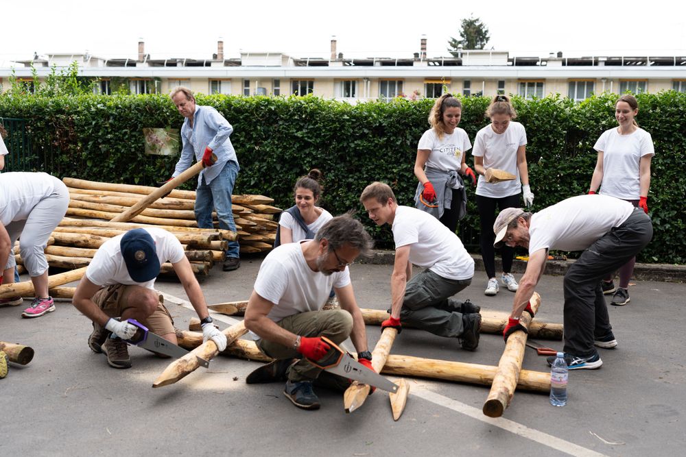 Students working together building wooden structures on the ground during an outdoor group project.