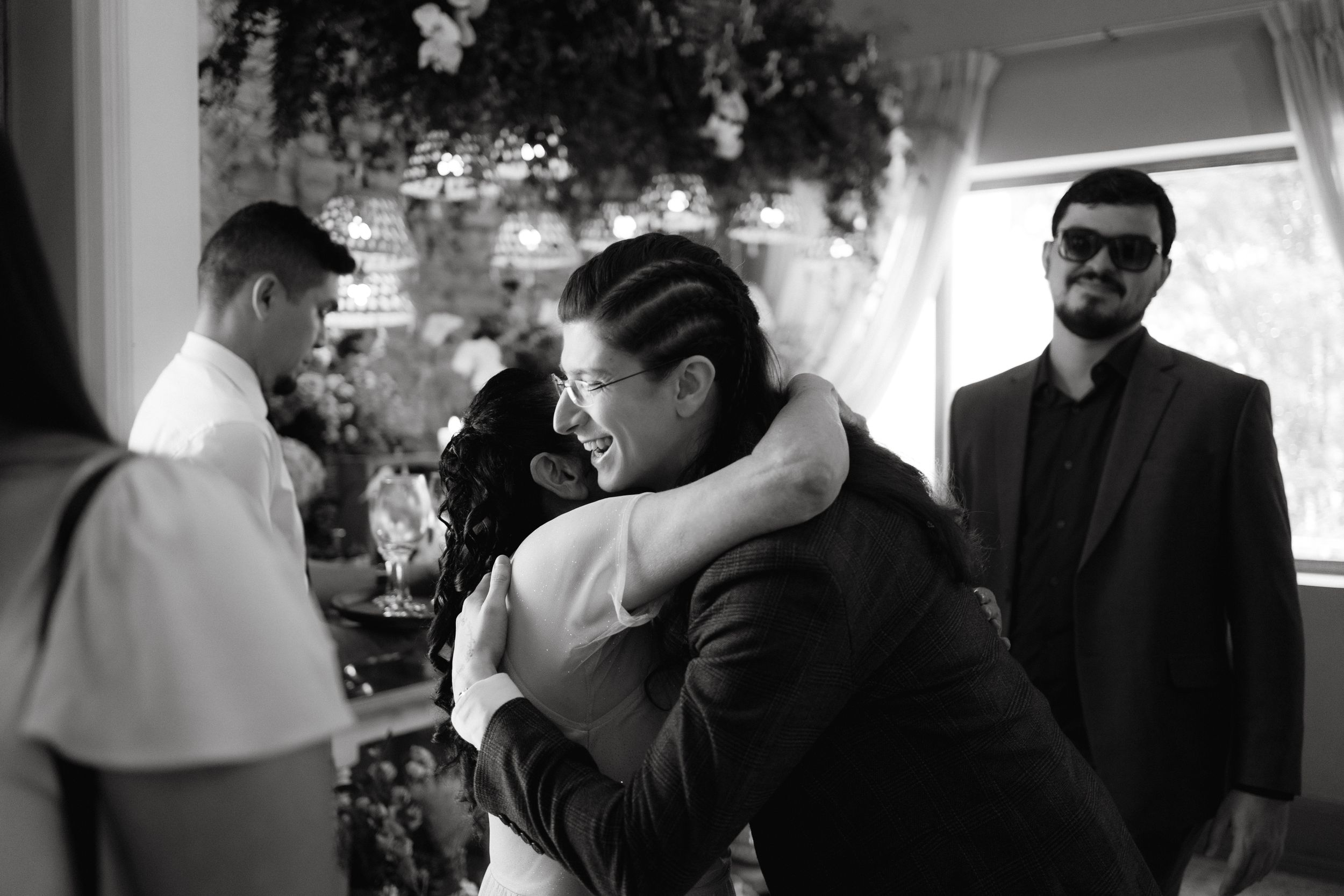Black and white candid moment during wedding ceremony with floral backdrop.