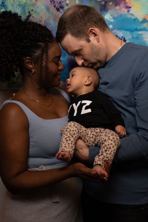 Intimate family moment with baby against colorful painted wall background.