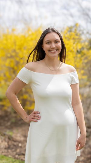 Outdoor portrait in a white dress with yellow forsythia flowers blooming in the background.