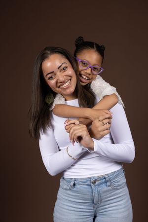 Two people in white tops and jeans sharing playful hugs and laughter during a photo session.