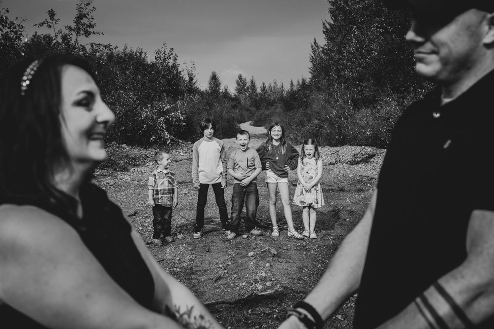 Black and white photo of couple in foreground with group visible in background outdoors.