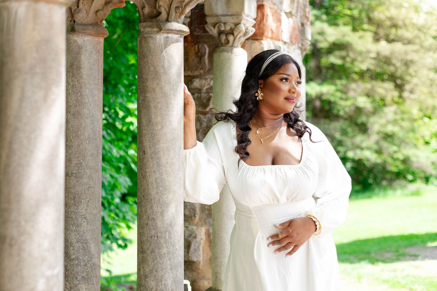 Bridal portrait under stone archway with lush greenery in background.