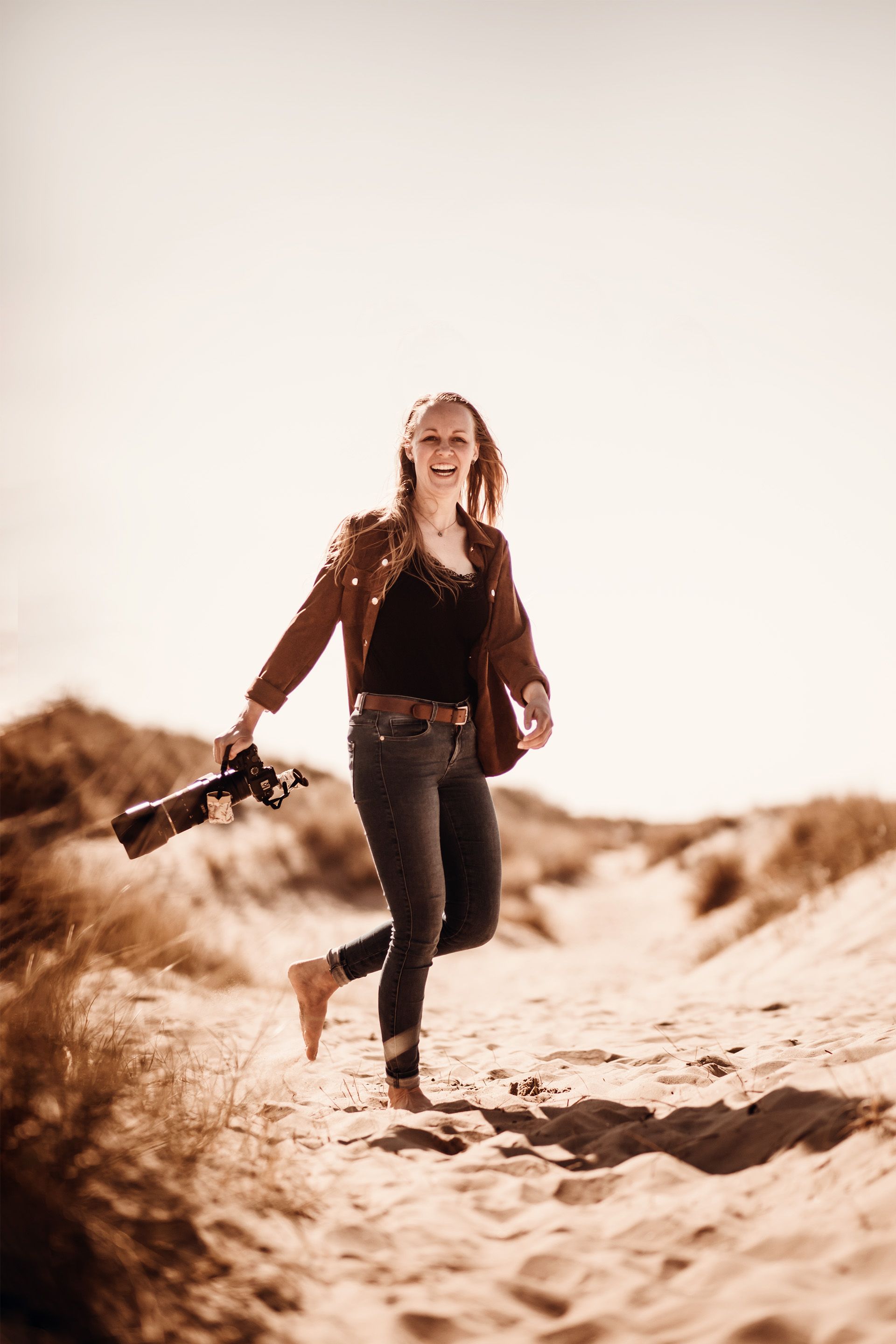 Madlen Becker fröhlich mit Kamera am Sandstrand in Renesse