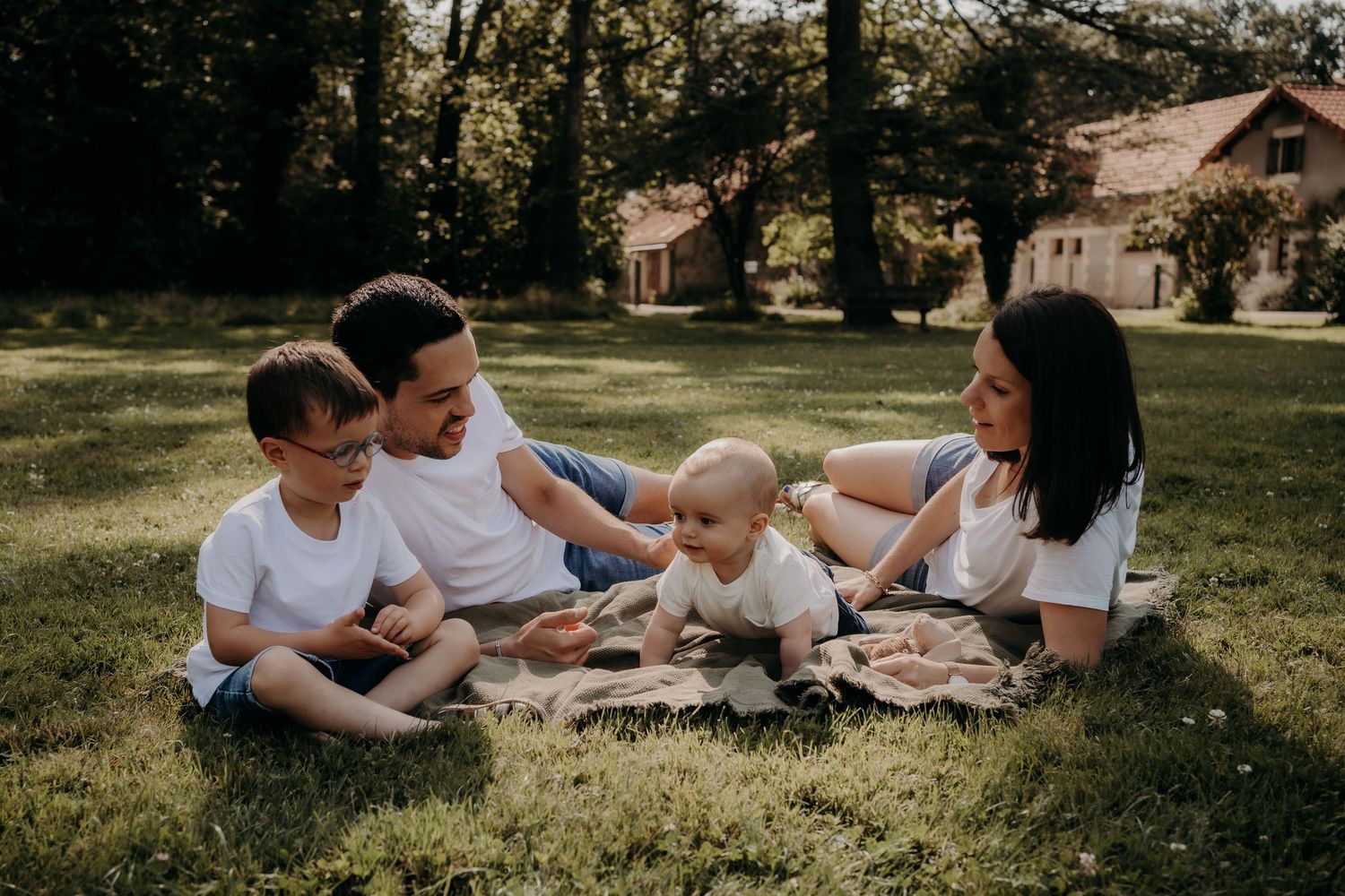 Family relaxing together on grass during outdoor lifestyle photoshoot.