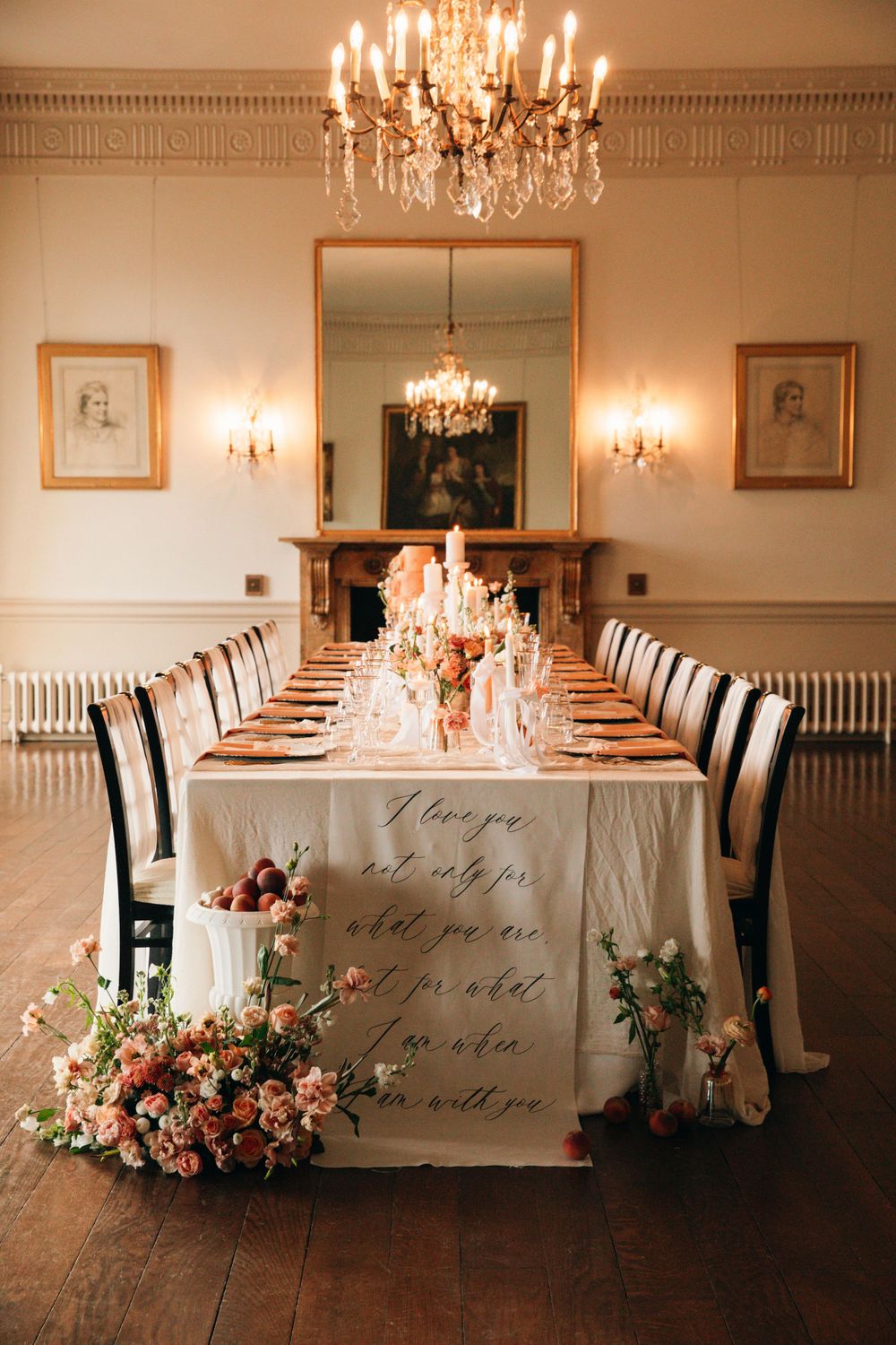 Elegant wedding reception table with chandelier and calligraphy tablecloth in a formal dining room.