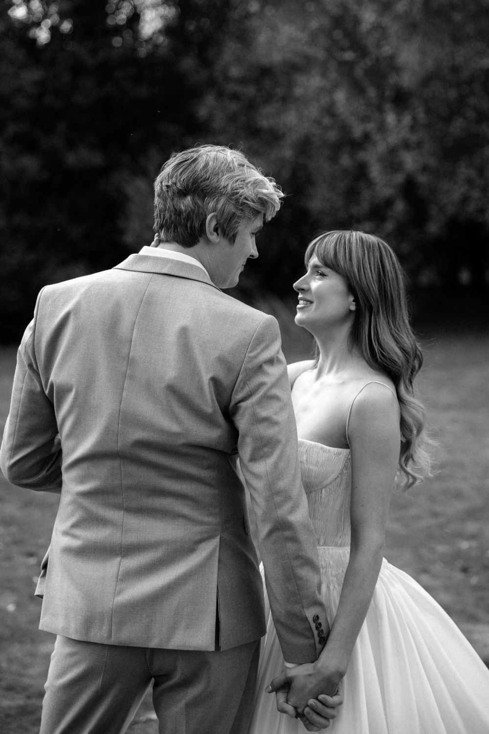 Black and white wedding photo capturing a loving gaze between newlyweds outdoors.