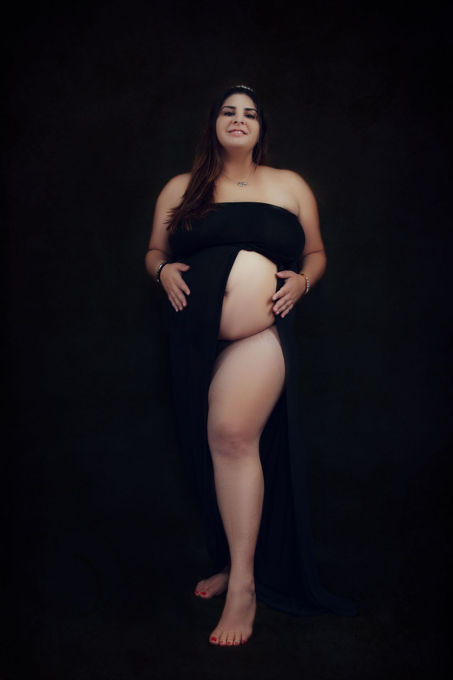 Woman poses dramatically against dark background in artistic portrait session.