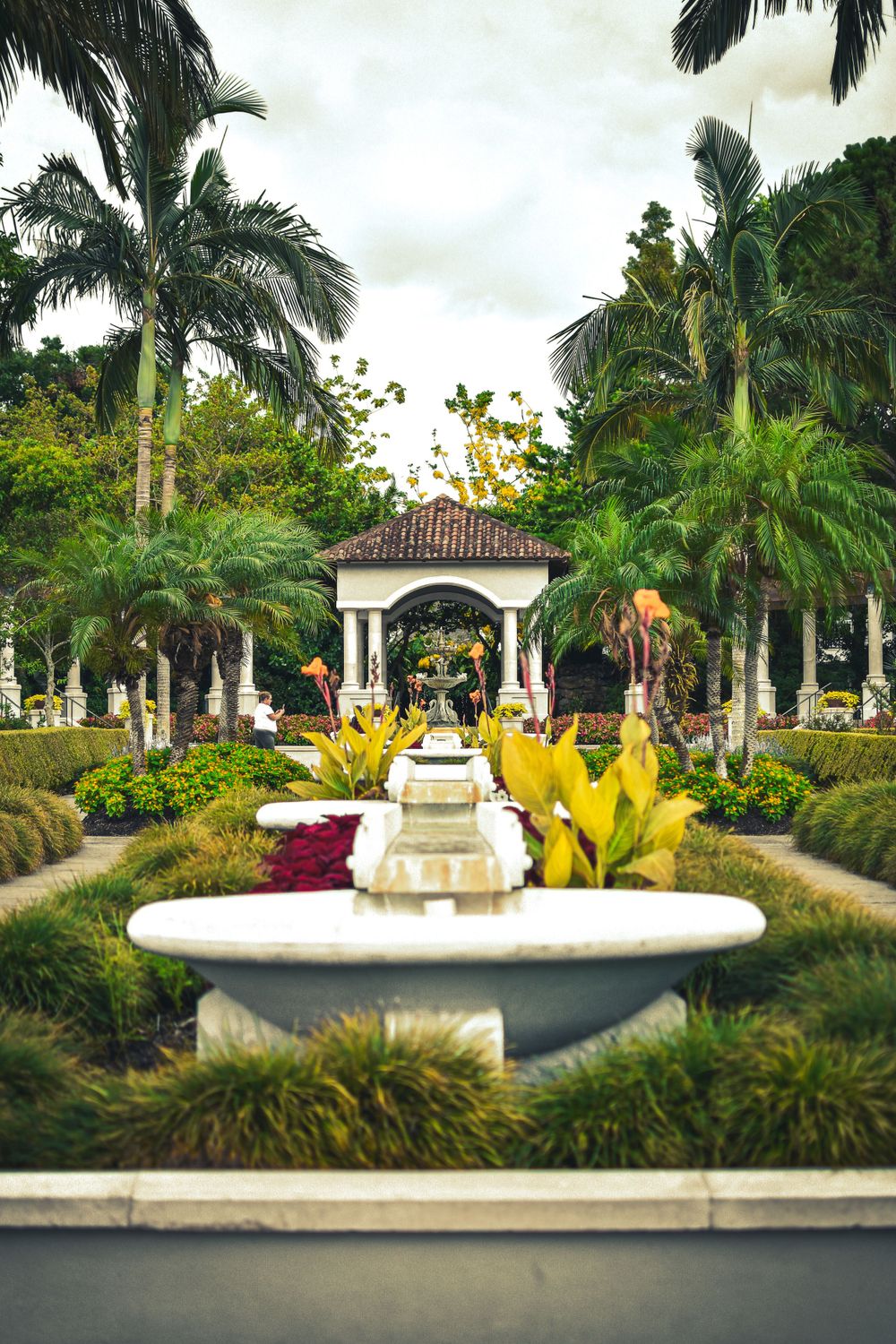 A Florida Botanical garden with rich green palm trees and beautiful white fountain and structures