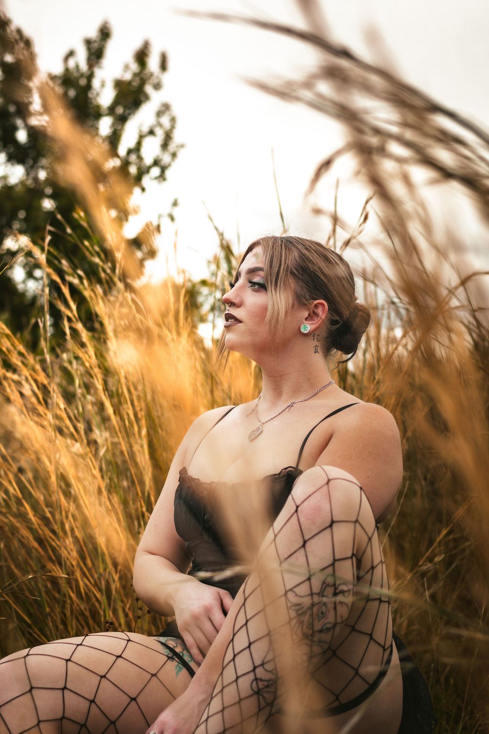 woman sitting in a wheat field staring off into the distance
