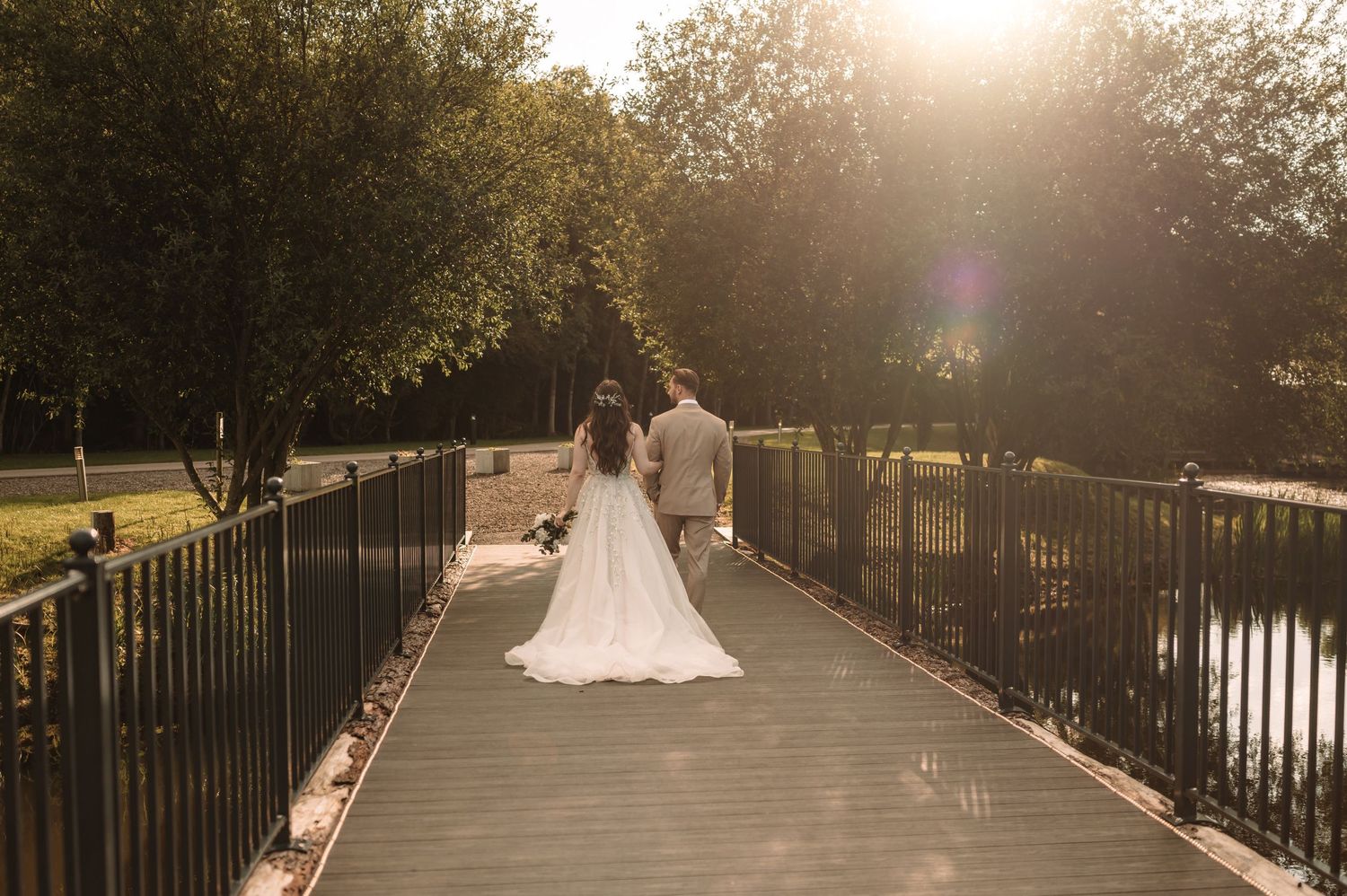 Newlyweds share a romantic moment on a wooden bridge during golden hour.