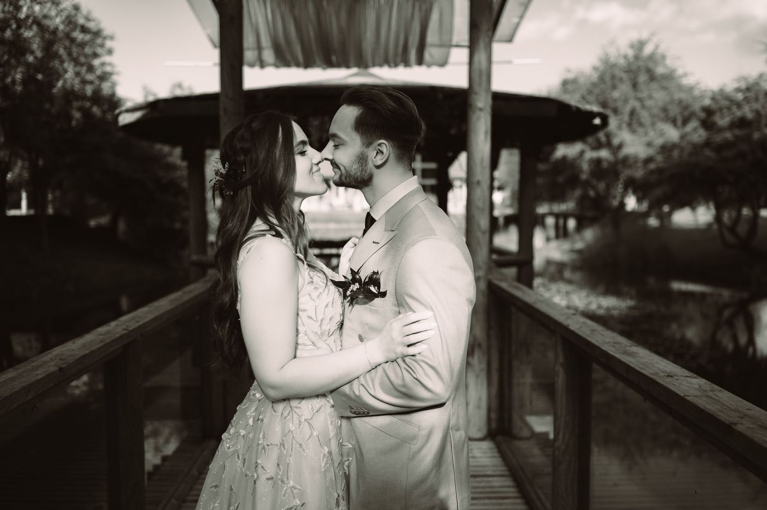 Black and white photo of a romantic wedding moment on a covered bridge.