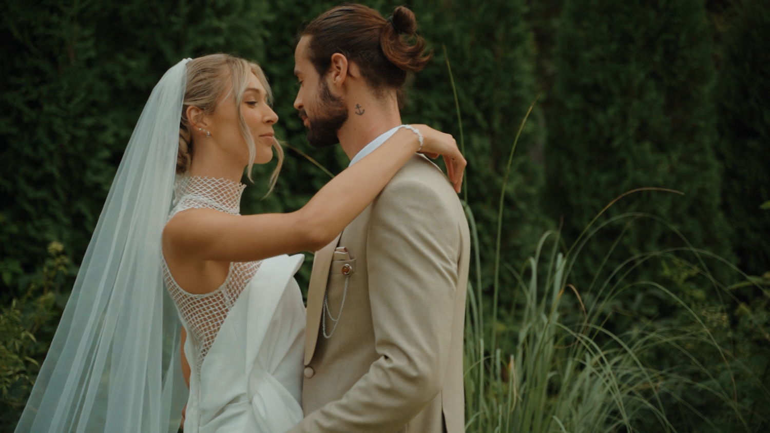 A couple in wedding attire shares intimate moments in a lush garden setting during their outdoor wedding celebration.