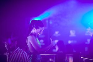 Concert pianist performing at night under dramatic blue and purple stage lighting.