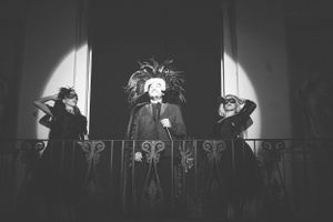 Dramatic black and white silhouette of performers on stage with spotlights.
