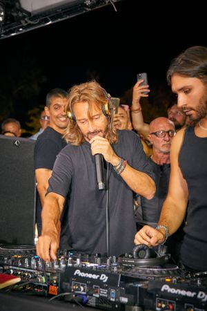 Crowded nightclub scene with DJ working Pioneer equipment.