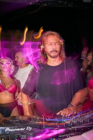 DJ performing at Pioneer equipment under purple club lights.