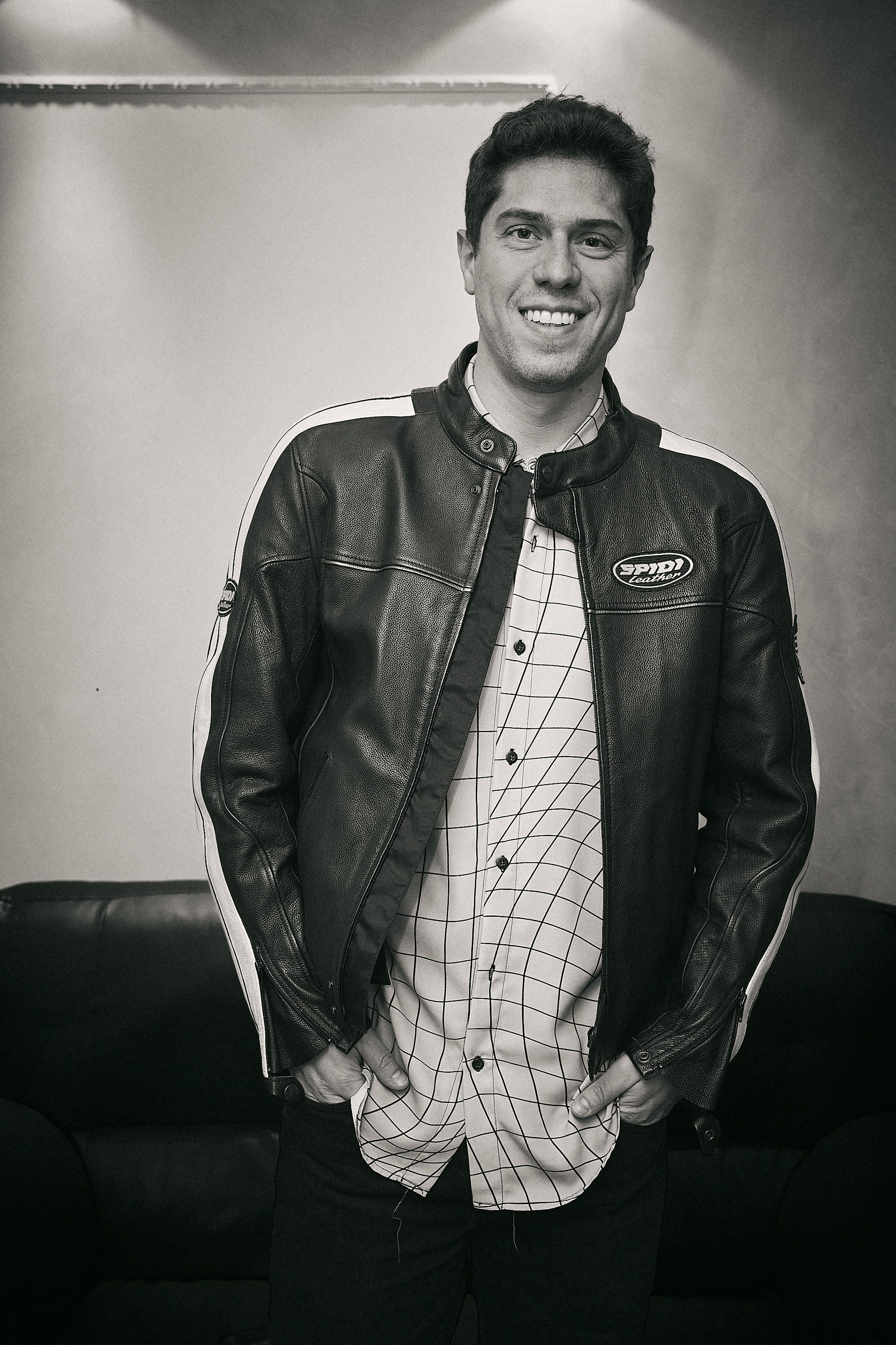 Black and white portrait of performer wearing leather jacket and plaid shirt.
