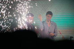Concert performer on stage with dramatic sparkler effects and green lighting in the background.