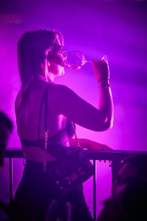 Silhouette of a performer singing on stage illuminated by vibrant purple lighting.