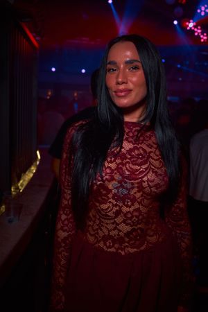 Nightclub scene with person in red lace dress under dramatic lighting.