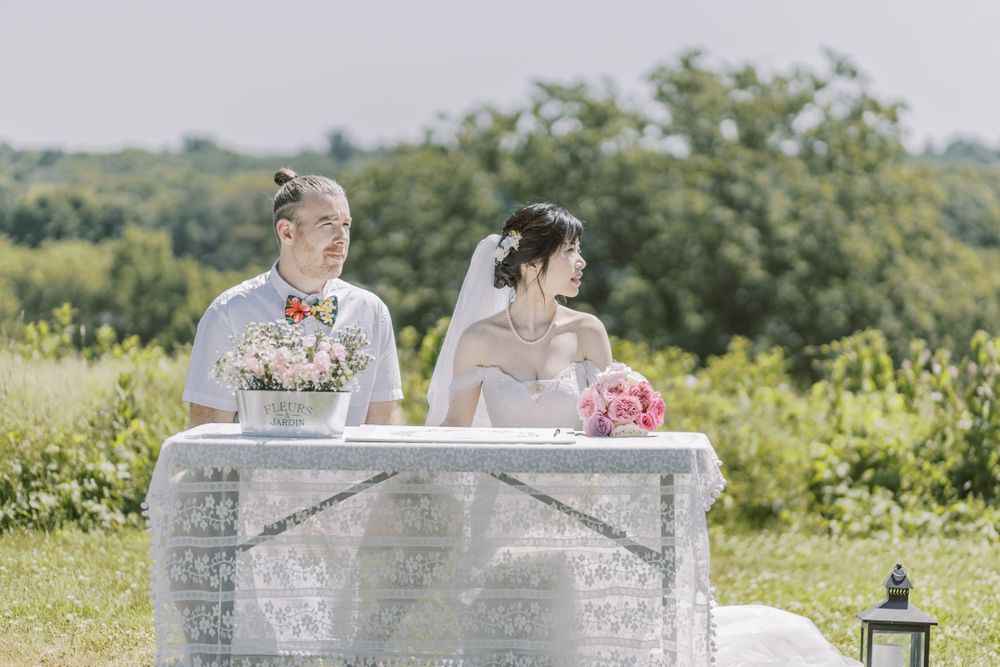 Elegant white vintage seating arrangement at outdoor hilltop wedding ceremony.