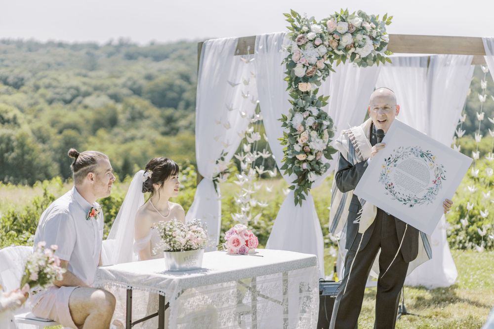 Ornate white vintage settee decorated with flowers at outdoor wedding ceremony.