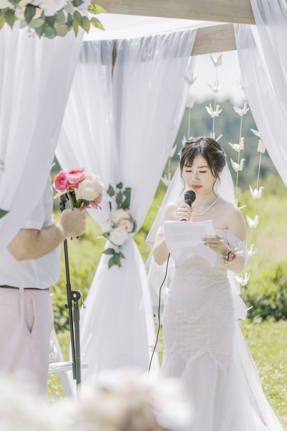 An intimate outdoor wedding ceremony with flowing white curtains and hanging paper butterflies.