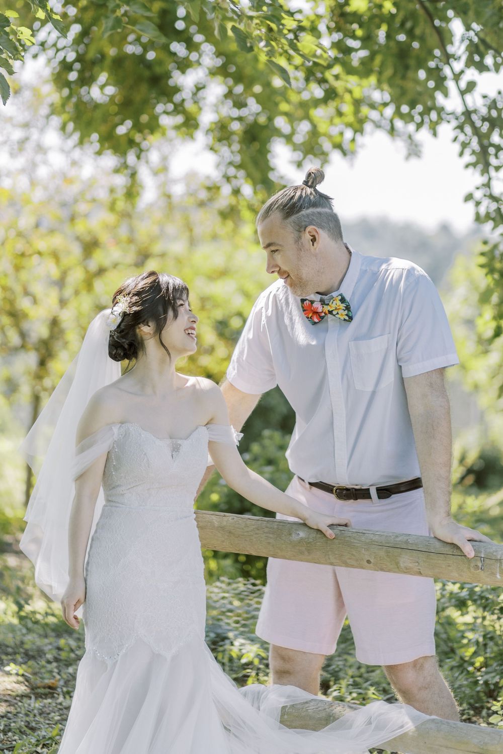A romantic outdoor wedding photoshoot under green trees on a bright summer day.