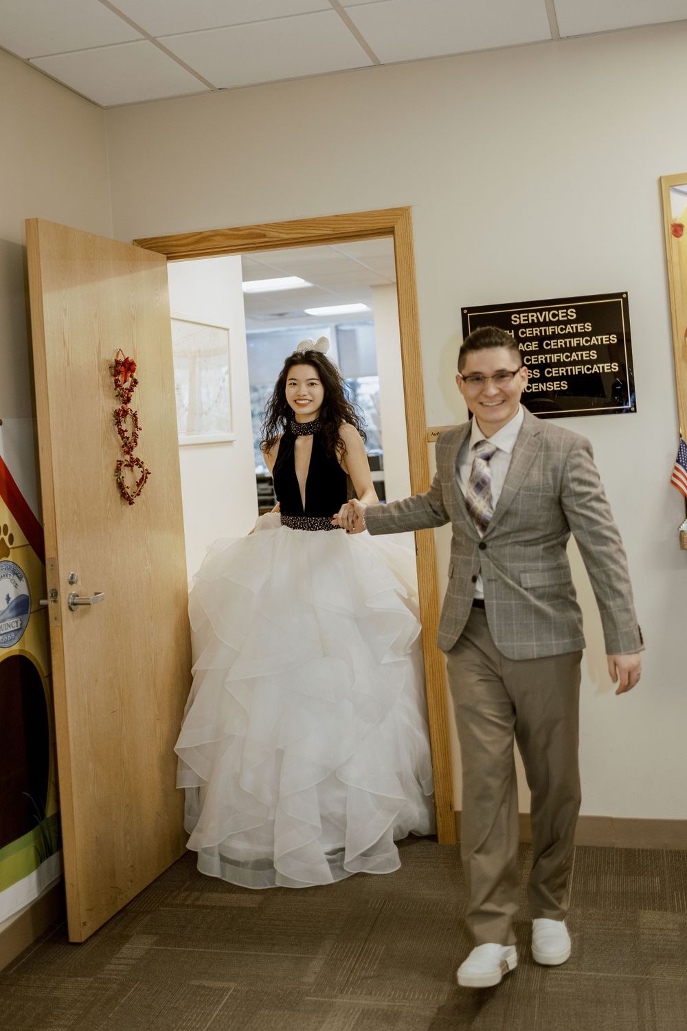 Wedding couple shares fun moment by office doorway.