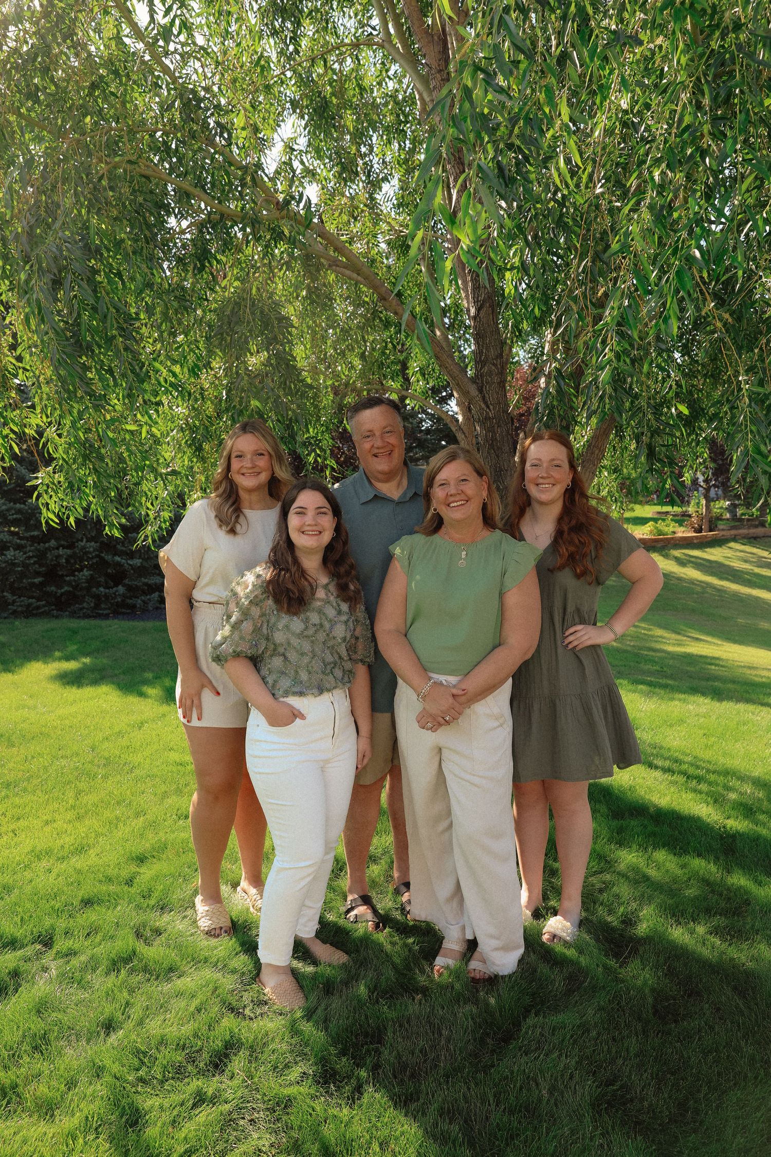 Group photo under willow tree branches on sunny summer day.