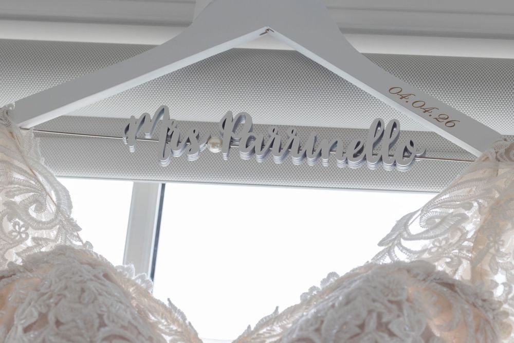 Close-up of a custom white bridal hanger reading Mrs. Hainneville with lace wedding dress below.