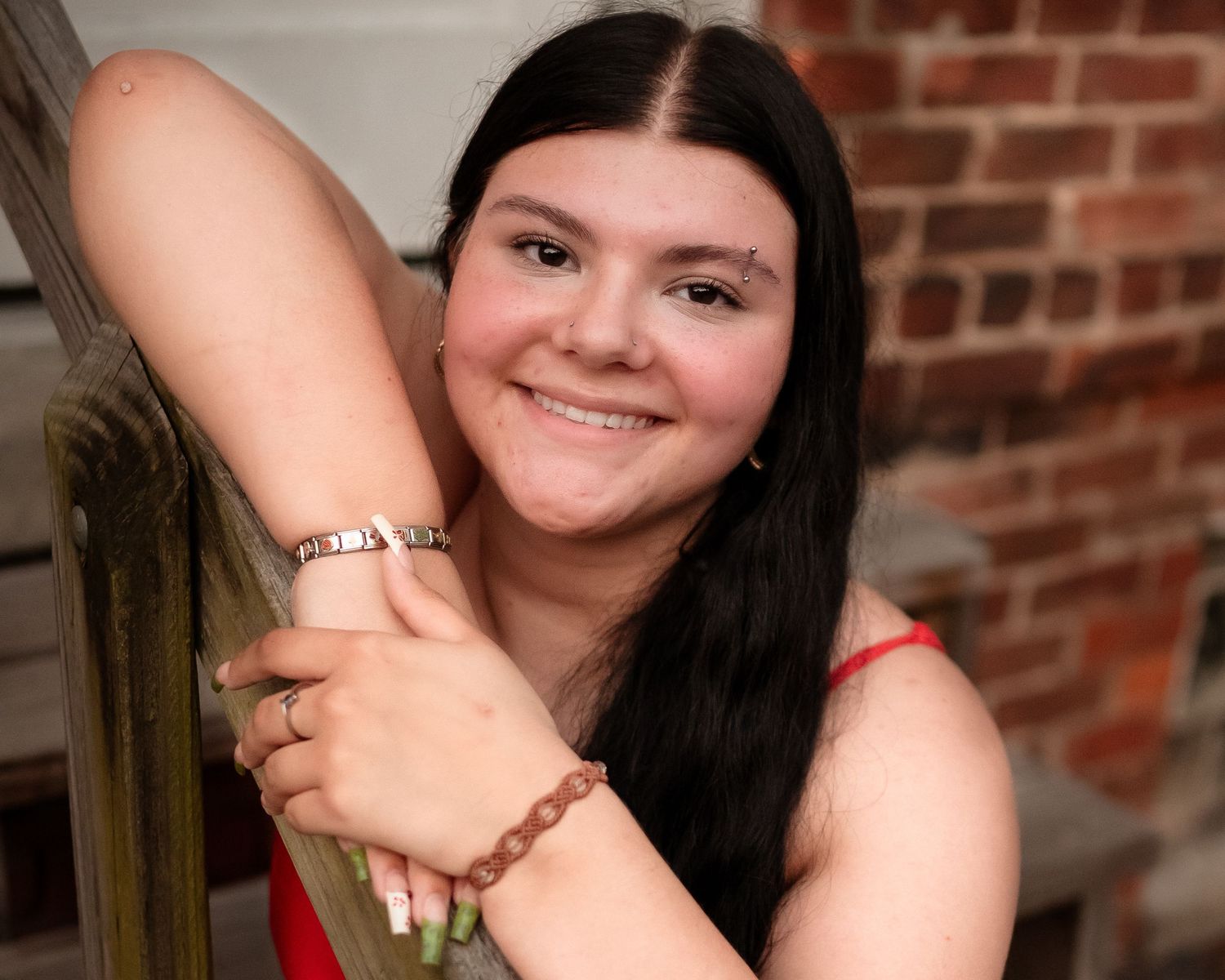 A series of similar portrait style photos taken against a brick wall background with red tones.