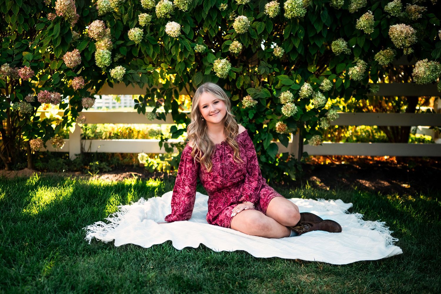White and yellow roses bloom in a peaceful garden setting with a blanket on the grass.