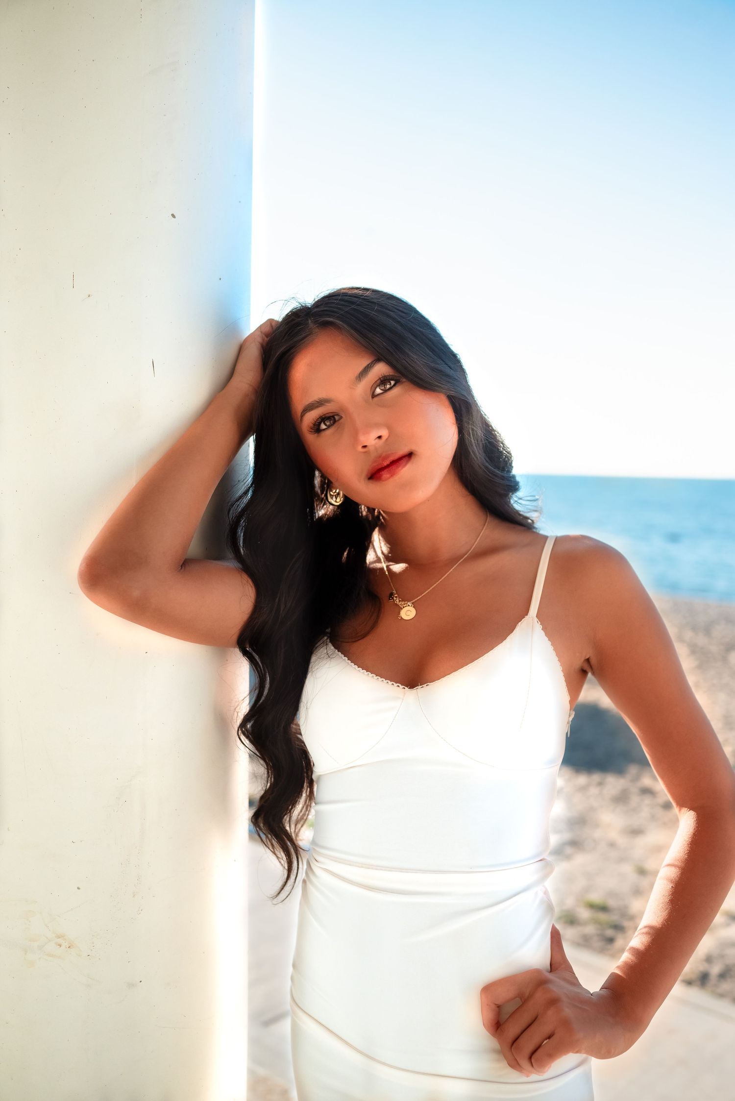 A person in a white spaghetti strap top poses against a bright background in a creative photo series.