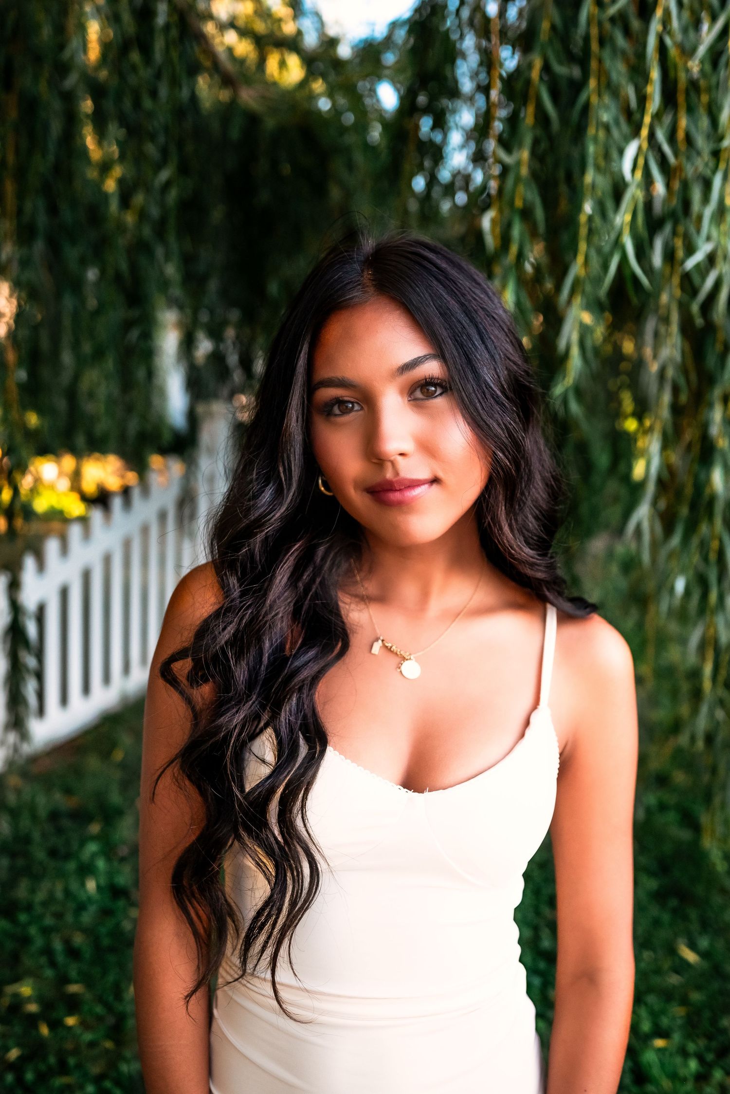 A series of outdoor portrait photos showing someone in a white sleeveless top posing against a backdrop of willow trees.