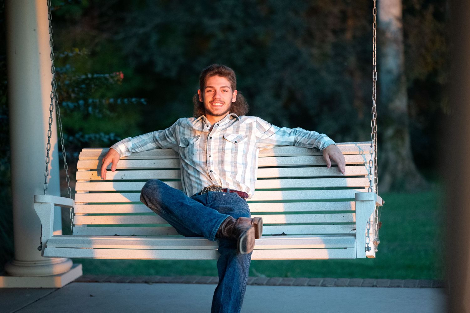 Relaxed poses on white porch swing during outdoor photo session.