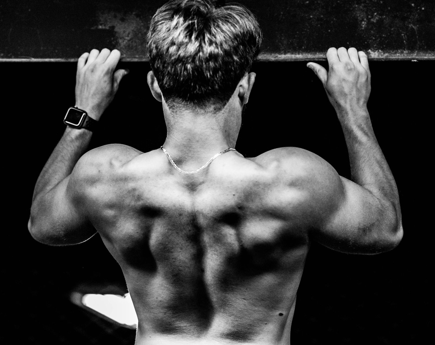 Series of black and white images showing muscular back during pull-up exercises.