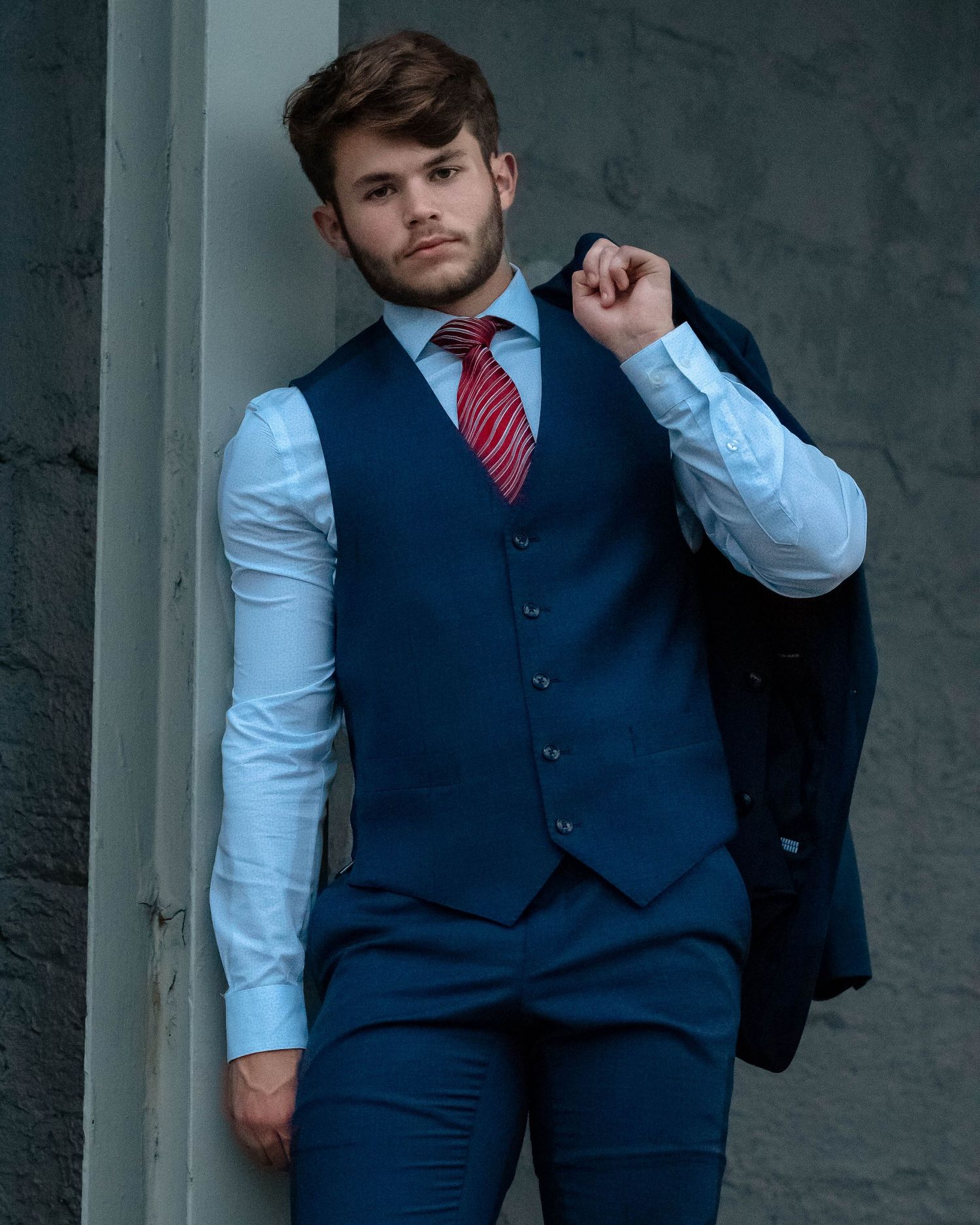 Close-up fashion shots featuring navy vest, white shirt, and red tie combination.
