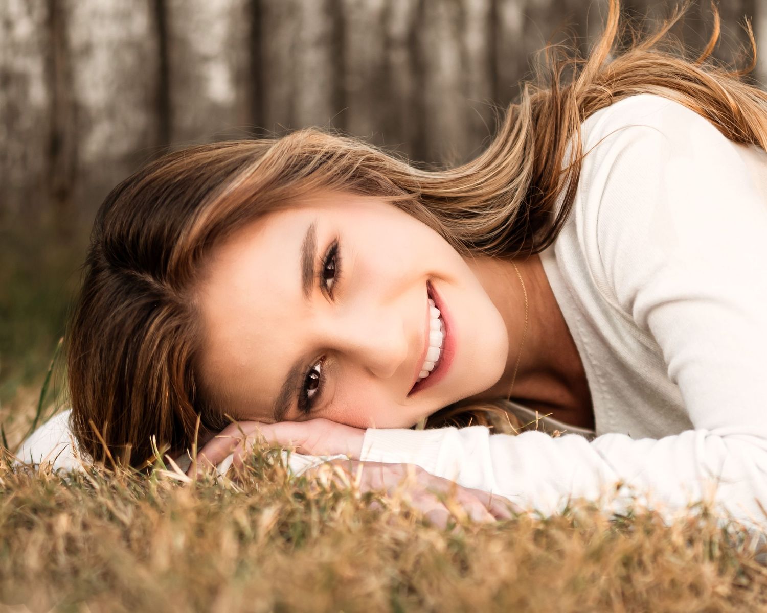 A person lying in tall grass during golden hour with soft natural lighting.