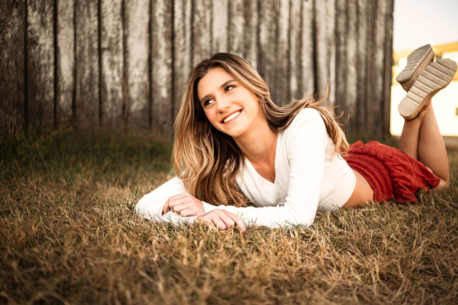 A person lying on grass in a dreamy outdoor portrait setting.