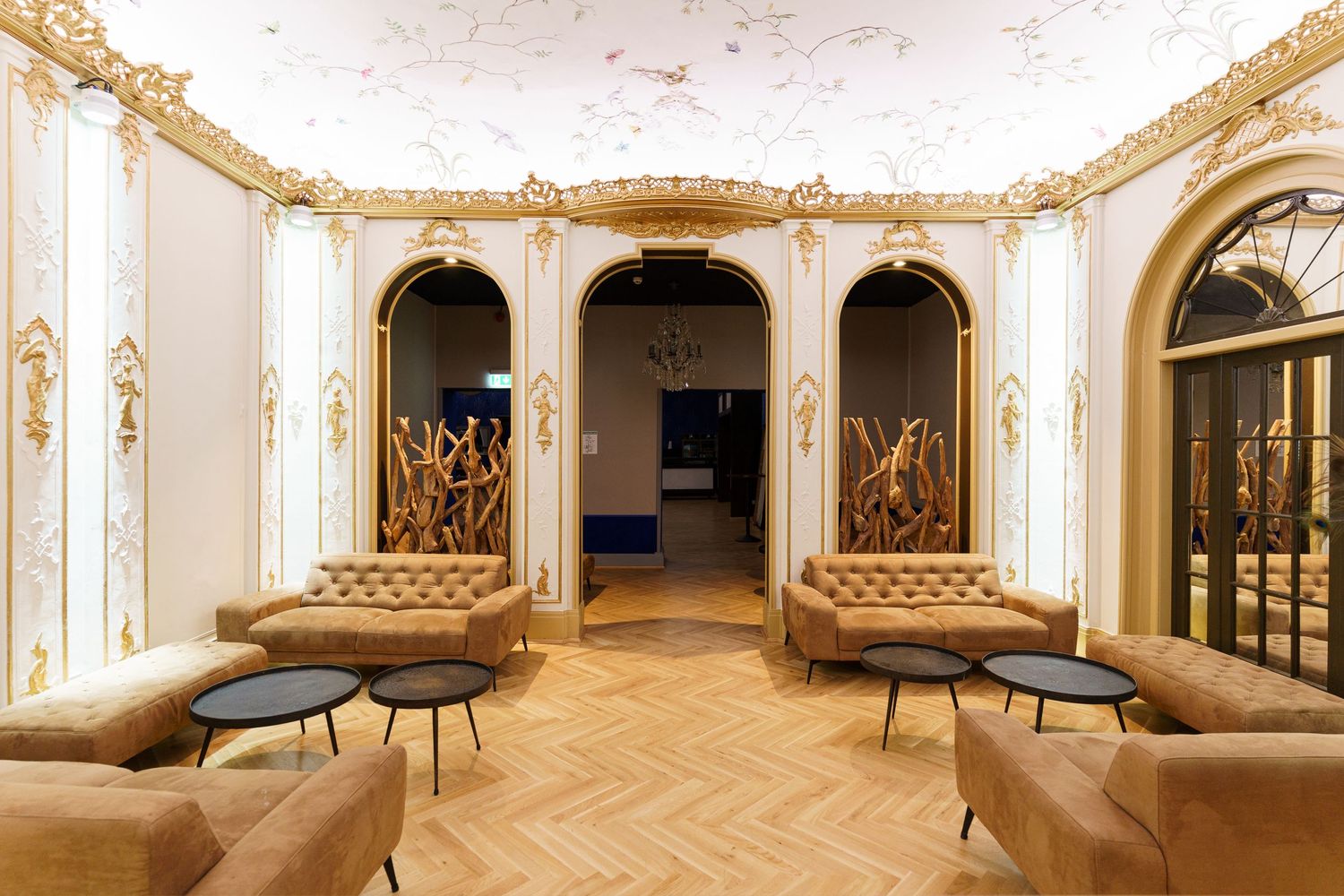Grand ballroom interior with white and gold decor featuring arched windows, ornate moldings and polished wood floors. Parkhotel | Dresden