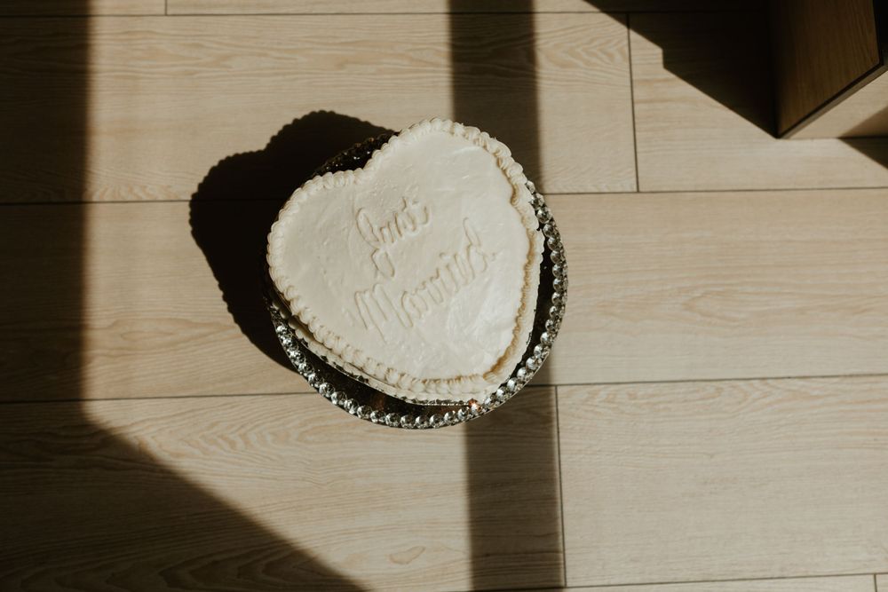 Heart-shaped wedding cake photographed in dramatic window light.